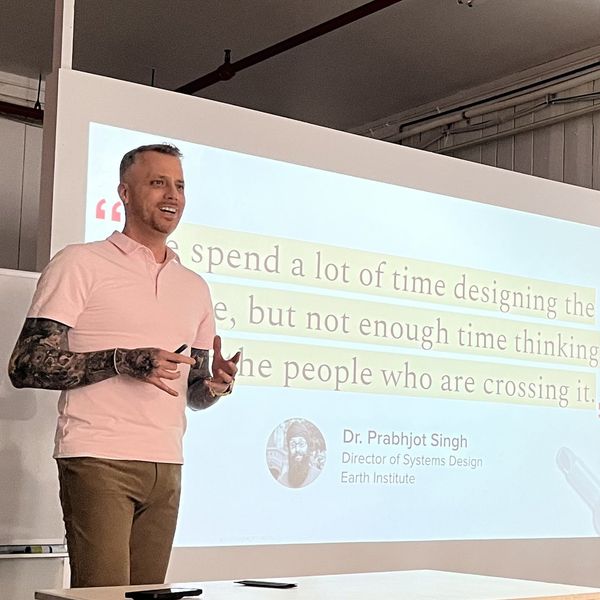 Jamie Gerrard presenting beside a projected quote from Dr. Prabhjot Singh: We spend a lot of time designing the bridge, but not enough time thinking about the people who are crossing it.