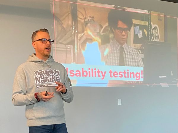 Jamie Gerrard presenting beside a projected slide reading Usability testing.