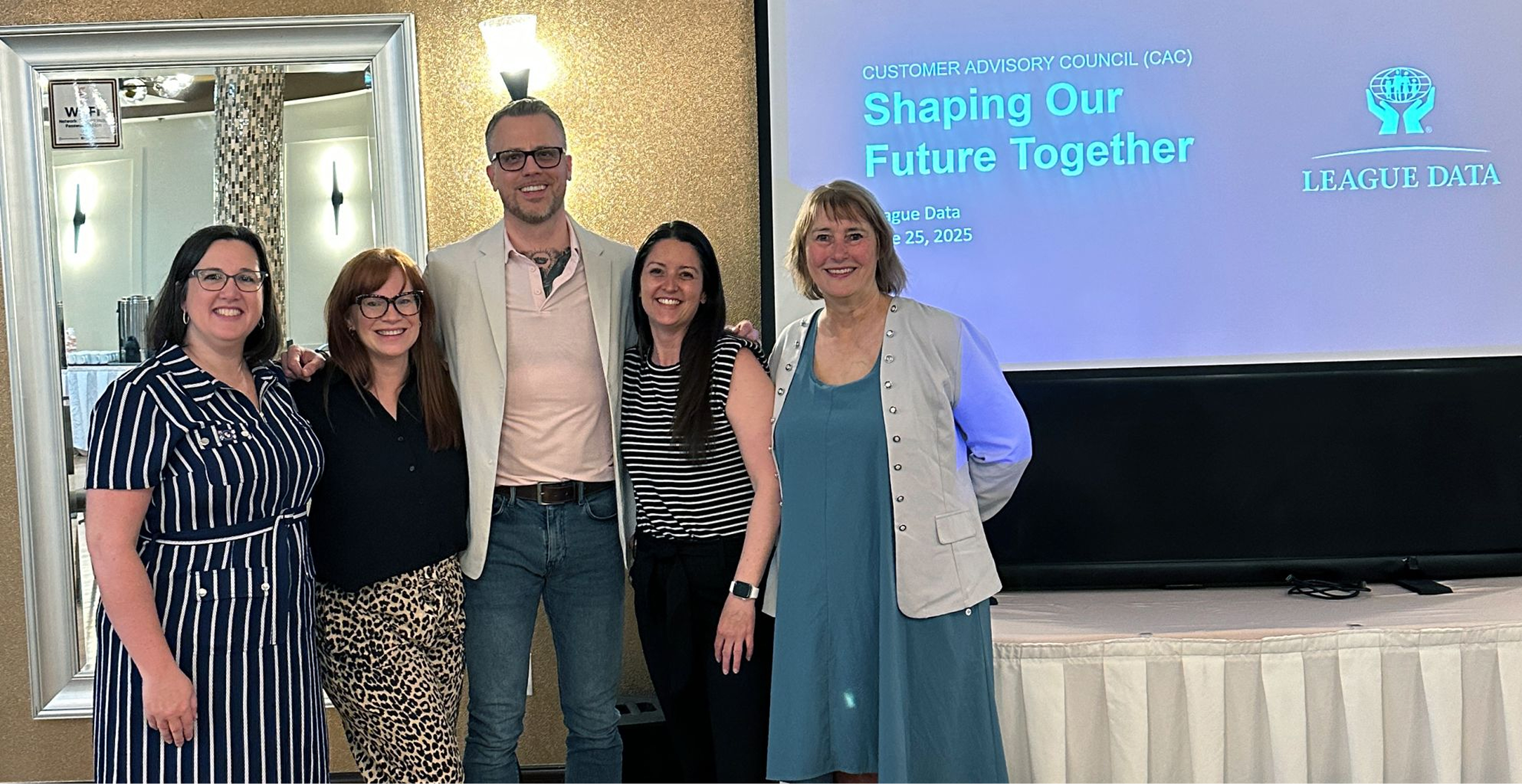 Jamie Gerrard with three members of League Data's Engagement team and their Head of Customer Experience in front of a screen reading Customer Advisory Council (CAC): Shaping Our Future Together.