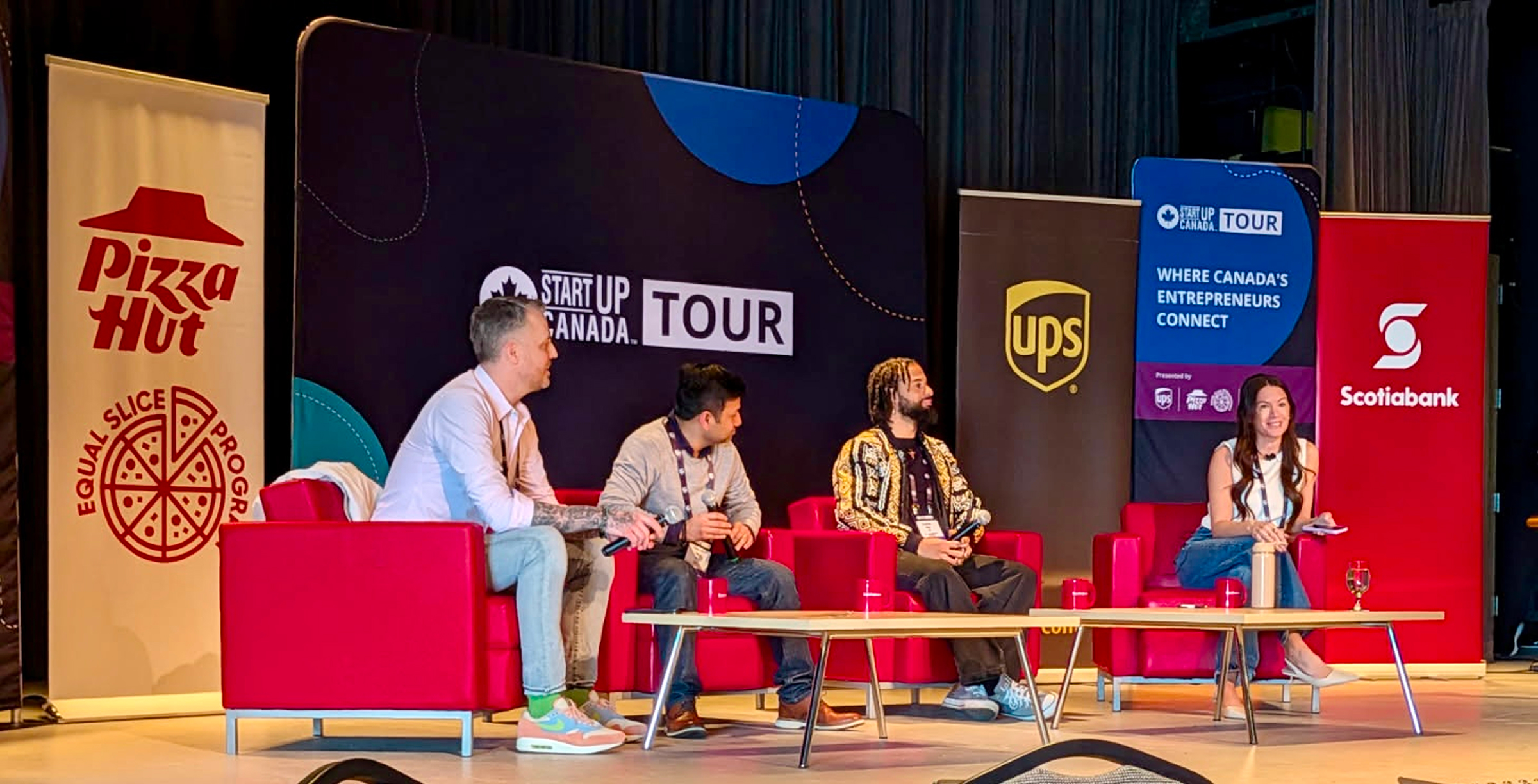 Three panelists seated on stage at the Startup Canada Tour stop in Halifax, with the moderator alongside them.